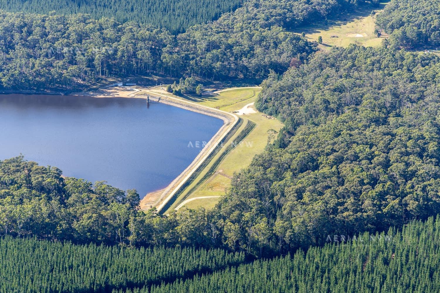 Aerial view of Bostock Reservoir dam wall and water storage surrounded by forest and plantation near Spargo Creek, Victoria.