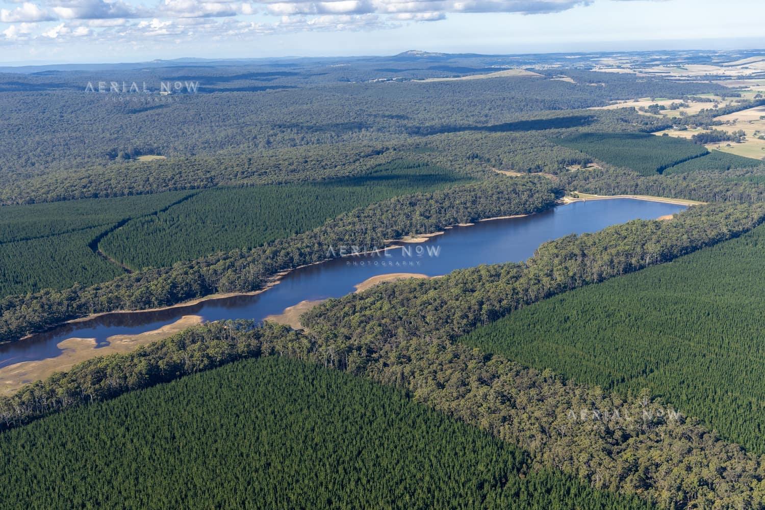 Aerial view of Bostock Reservoir with a narrow shoreline surrounded by dense forest and plantation land near Bolwarrah, Victoria.