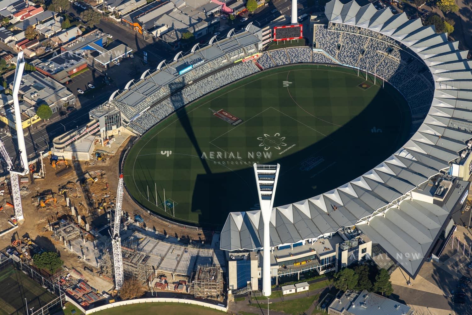 Aerial view of GMHBA Stadium at Kardinia Park in South Geelong with cranes, construction works, existing stands and the oval playing surface visible.
