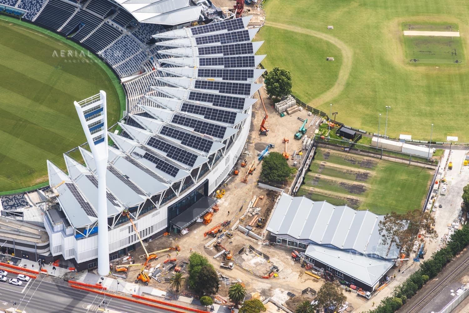 Aerial view of GMHBA Stadium at Kardinia Park in South Geelong, showing grandstands with rooftop solar panels, construction works and surrounding sports fields.