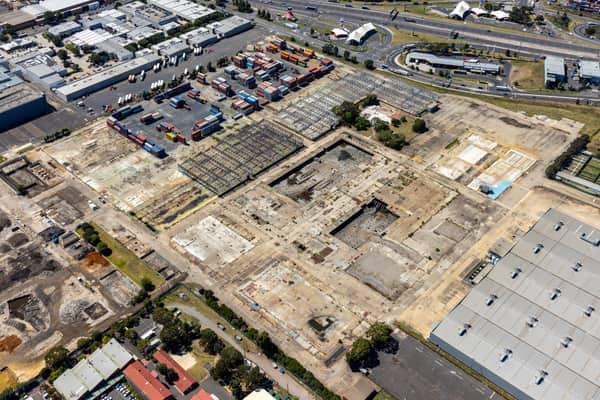 Aerial view of the former General Motors Holden factory redevelopment site, with dismantled structures, container storage and the West Gate Freeway in Port Melbourne, Victoria.