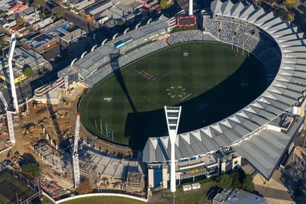 Aerial view of GMHBA Stadium at Kardinia Park in South Geelong with cranes, construction works, existing stands and the oval playing surface visible.