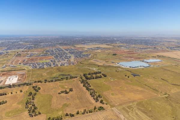 Wide aerial view over Boundary Road in Truganina, showing established warehouses, expanding housing estates, open farmland and the future Djeembana logistics precinct in Melbourne's west.