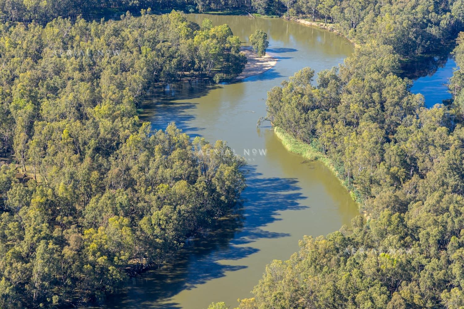 Aerial view of a winding Murray River bend bordered by dense river red gum woodland near Boomanoomana in New South Wales.