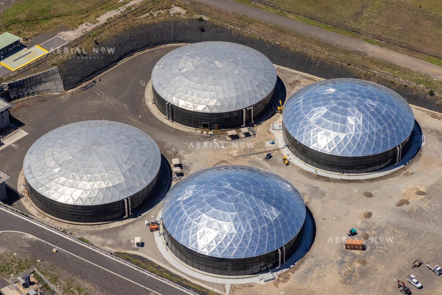 Aerial view of four large covered utility process tanks at an industrial infrastructure site in Craigieburn, with access roads, hardstand areas and service vehicles visible.