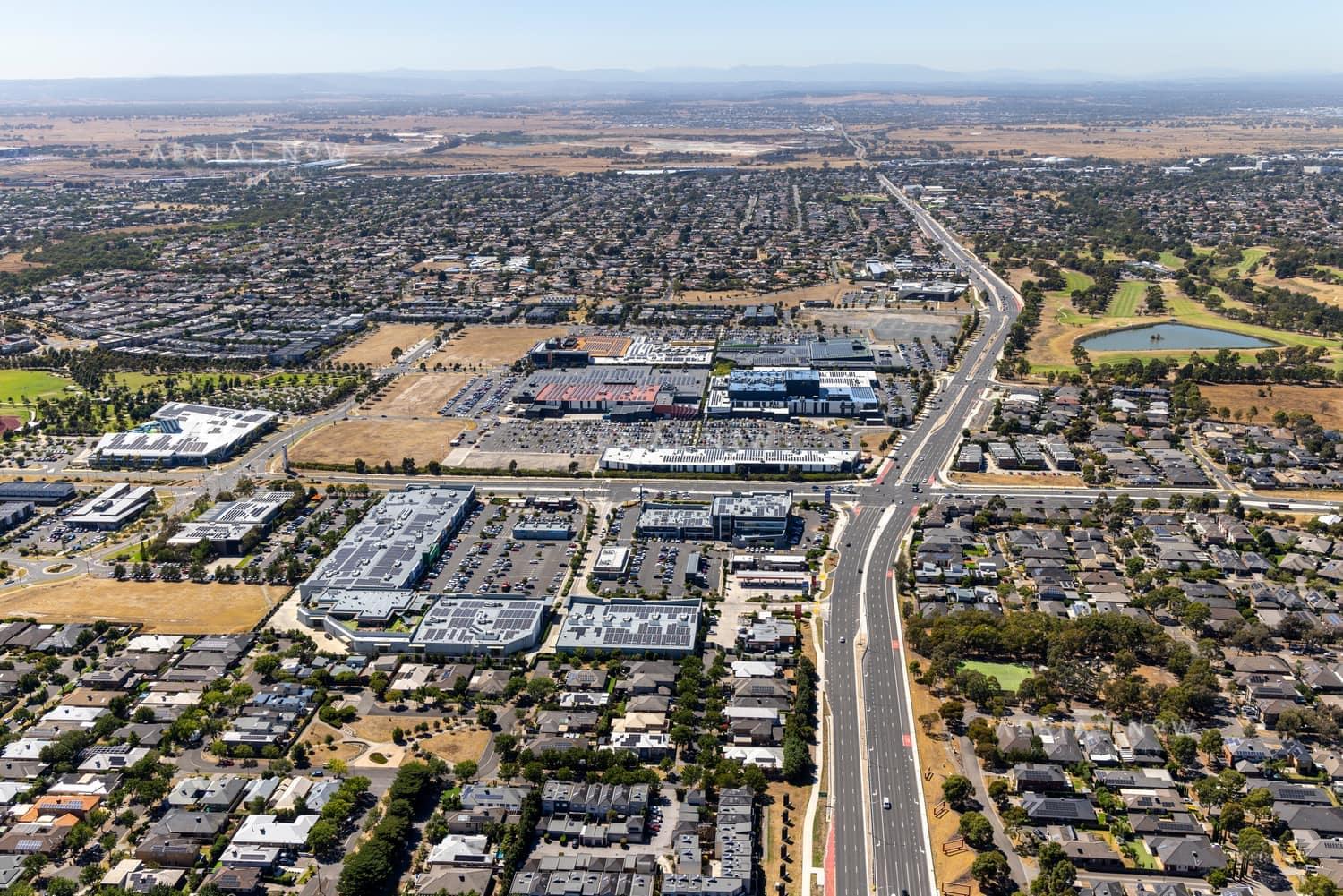 Aerial view of the Craigieburn Road commercial precinct in Craigieburn, with major roads, shopping centre car parks, housing estates and parkland visible.