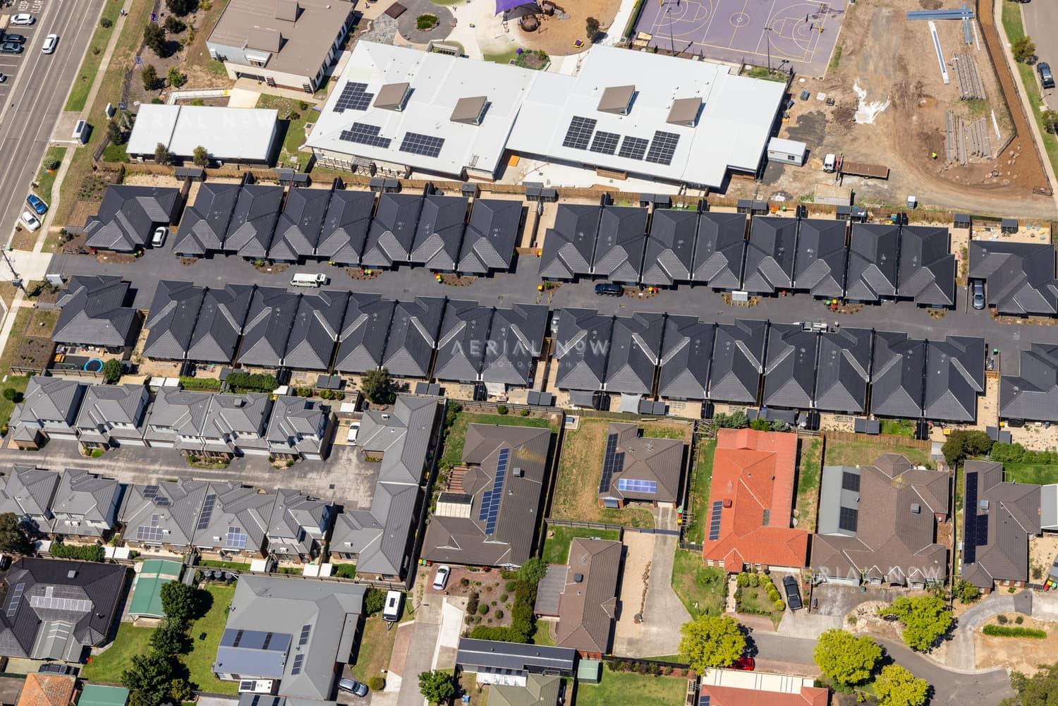 Aerial view of homes and townhouse rows near Marsh Crescent in Sunbury VIC, with rooftop solar panels, residential streets and nearby construction land visible.