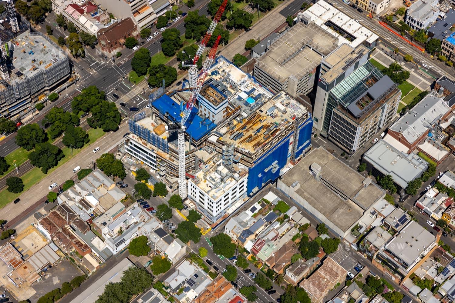 Aerial view of Australian Catholic University’s Saint Teresa of Kolkata Building under construction in Fitzroy on 7 February 2022, with cranes and incomplete upper levels visible.