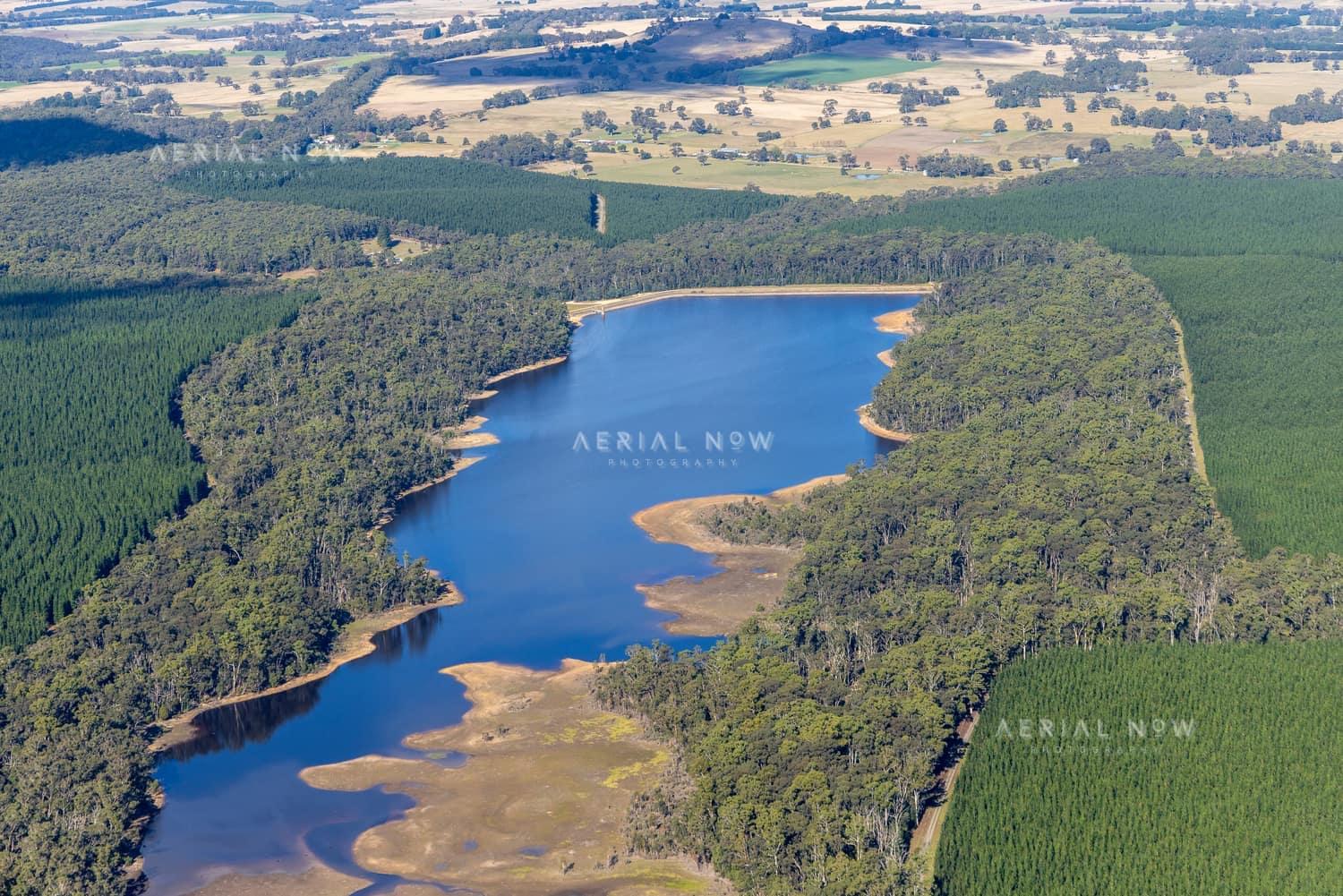 Aerial view of Bostock Reservoir near Spargo Creek, showing shallow inlet wetlands, surrounding bushland, plantation forest and rural farmland beyond.