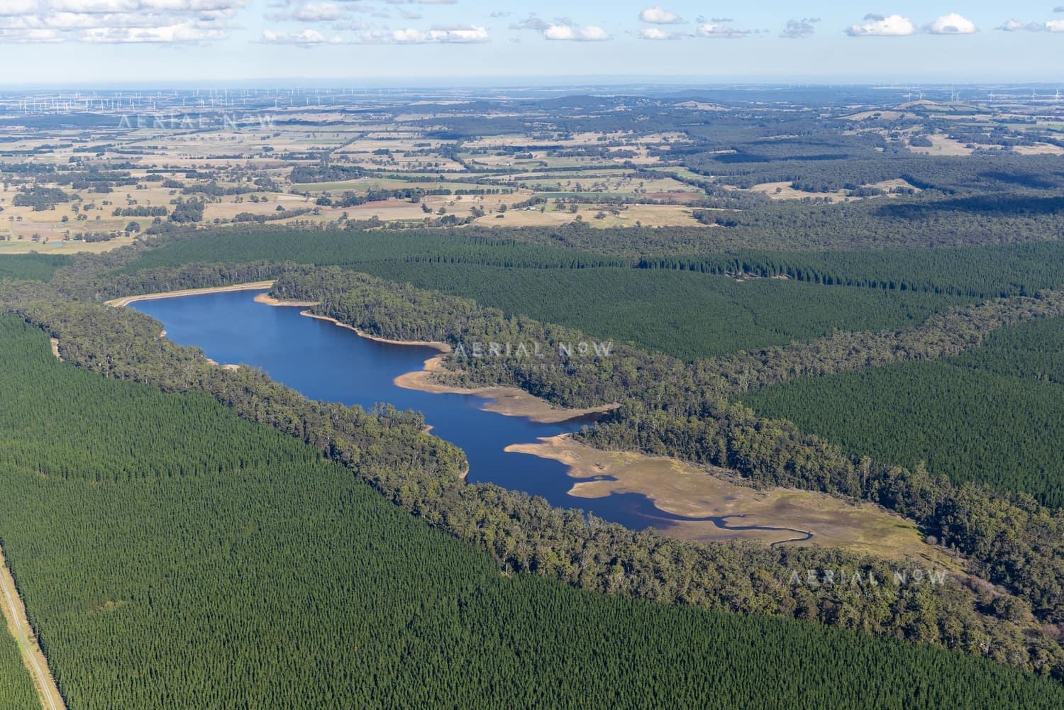 Aerial view of Bostock Reservoir at Spargo Creek, with blue water, exposed shoreline, surrounding native forest and plantation country.