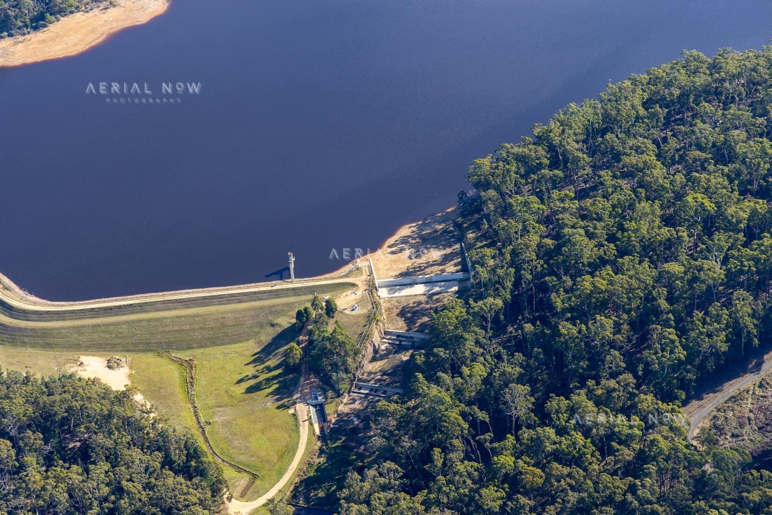 Aerial view of Bostock Reservoir showing the dam wall, spillway works, access track and forested shoreline at Bunding, Victoria.