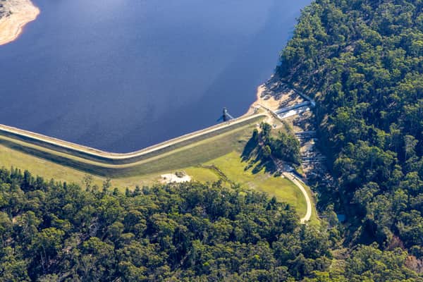 Aerial view of Bostock Reservoir in Bunding VIC, showing the curved dam embankment, reservoir water, shoreline tracks and surrounding forest.