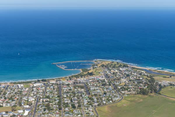 Aerial view of Apollo Bay Harbour, the coastal township, beaches, residential streets and farmland beside the Southern Ocean in Apollo Bay, Victoria.