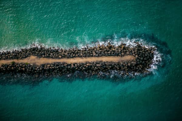 Aerial view of the southern Tweed River entrance training wall beside Fingal Head, with rock armour, access track and turquoise ocean water on the New South Wales north coast.