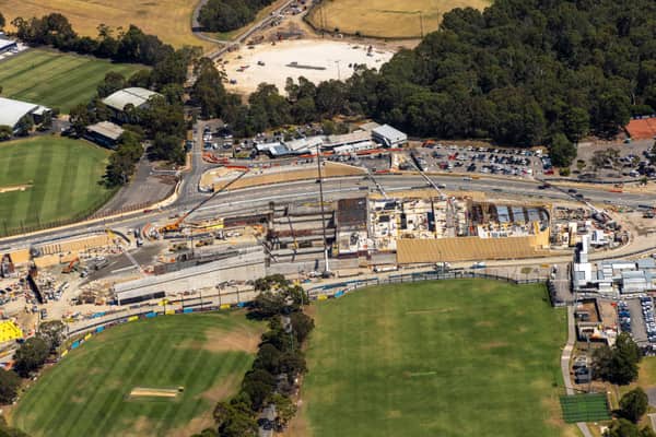 Aerial view of the North East Link construction worksite beside green sports fields and parkland near Balwyn Road in Bulleen, Victoria.