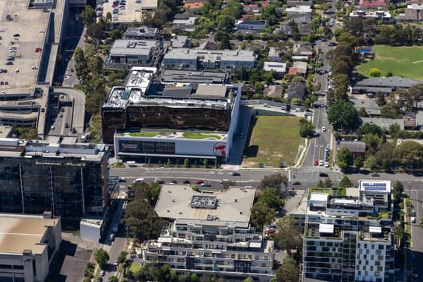 Aerial view of Bunnings Doncaster and the Mercure Melbourne Doncaster beside Westfield Doncaster, showing Doncaster Road, car parks, apartment buildings, traffic and the surrounding retail precinct.